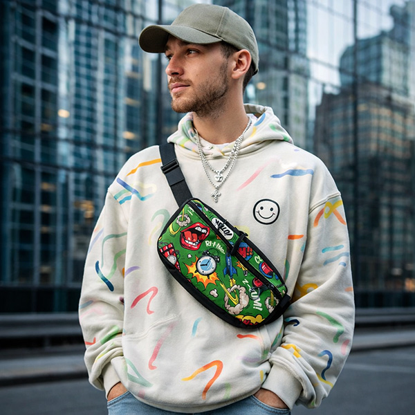 Большая сумка с ярким, сложным принтом на весь крой, чёрным ремнём и ремувкой на поясе мужчины