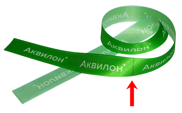 Атласная лента с зеленым фоном, на нем заметна более темная поперечная полоска, оборот бледный