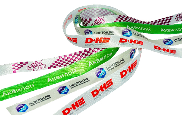 Белые атласные ленты с многоцветными логотипами и одна с зеленым фоном