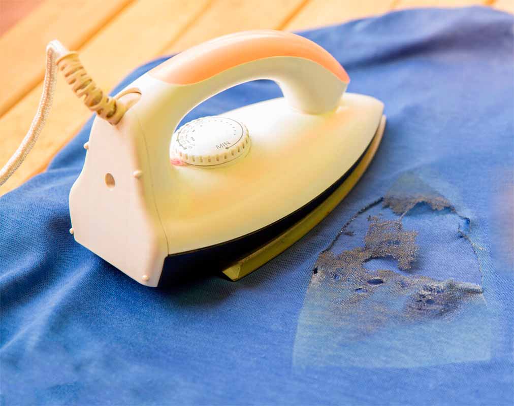 Синяя ткань с грязными дырками, расплавившимися от горячего утюга