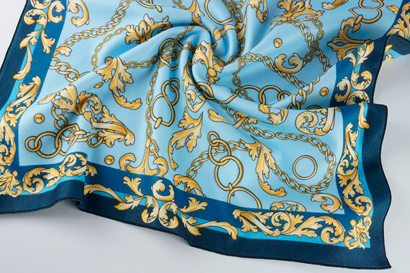 Сдержанный по цвету отпечаток орнамента из золотых цепей на голубом фоне, на бархатистой флисовой шали с крупными складками