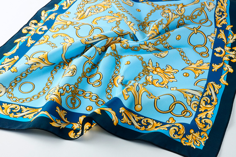 Отпечаток орнамента из золотых цепей на голубом фоне, глубоко насыщенный, на мокром шелке со красивыми складками