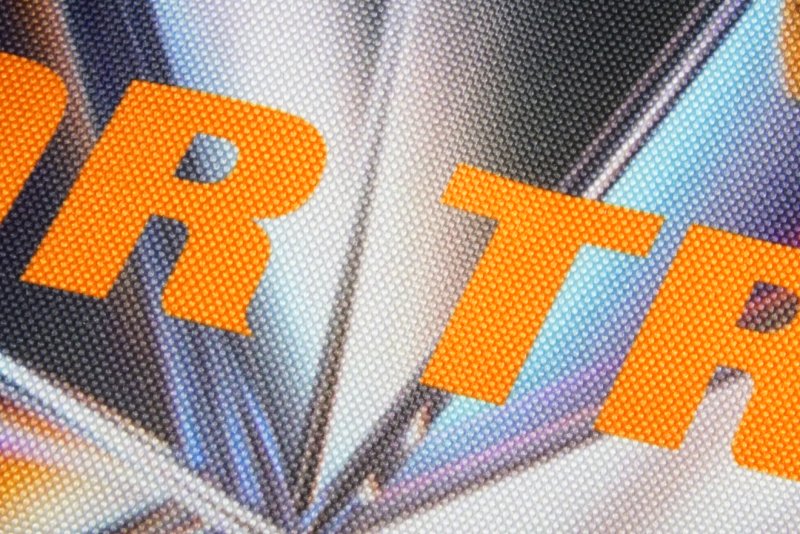 Крупнофактурная ткань с серо-голубым переливающимся принтом и оранжевыми буквами