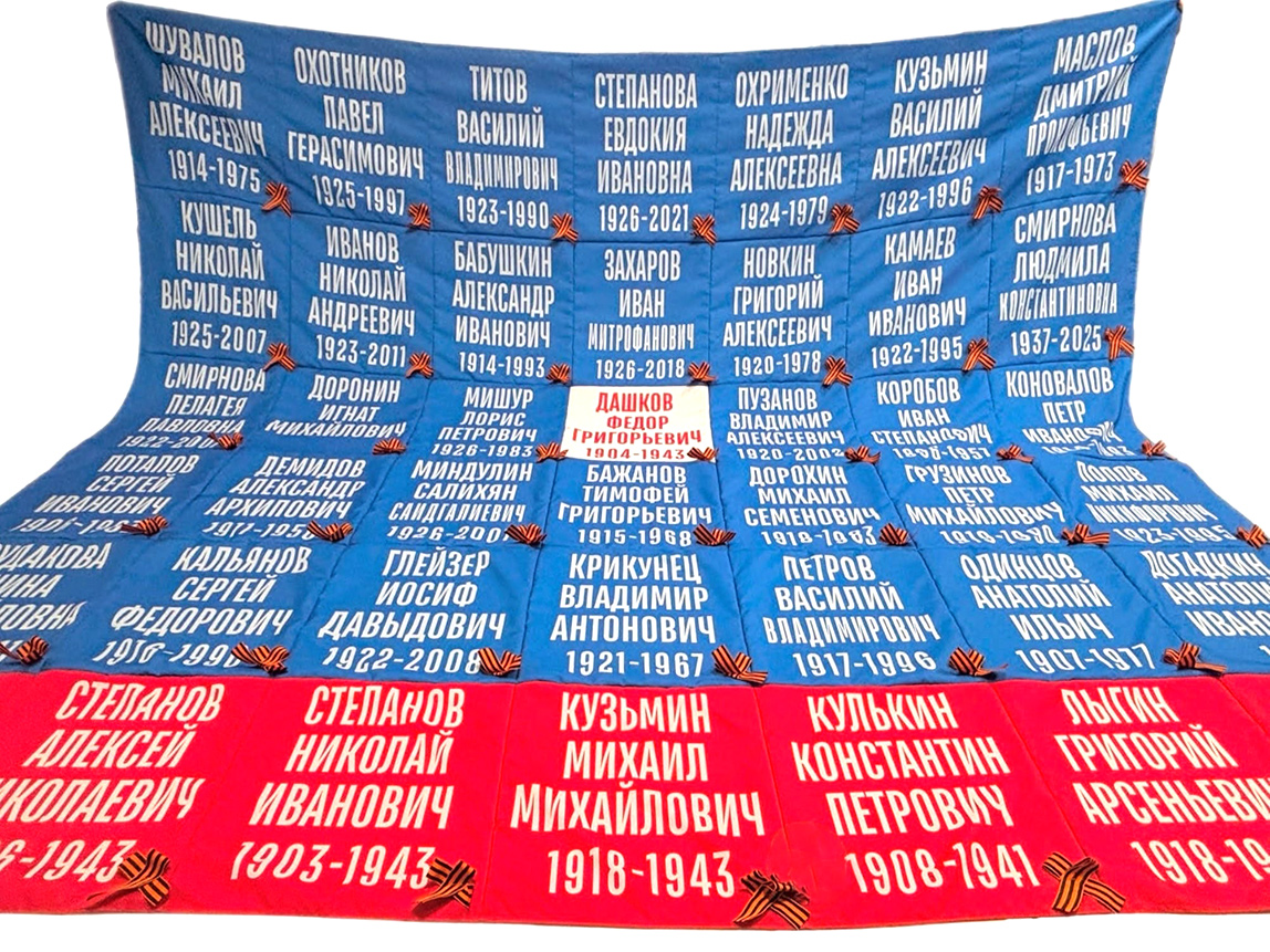 Большое полотно из синих и красных квадратов ткани с белыми именами, фамилиями и георгиевскими бантами 