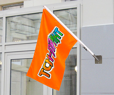 Маленький оранжевый флажок с ярким логотипом на стене в помещении