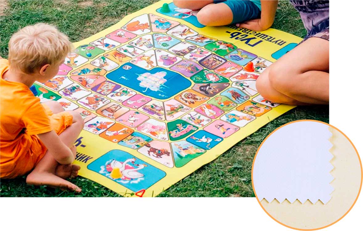 Игроки, сидят на траве, у игрового поля, напечатанного на виниловом полотне.